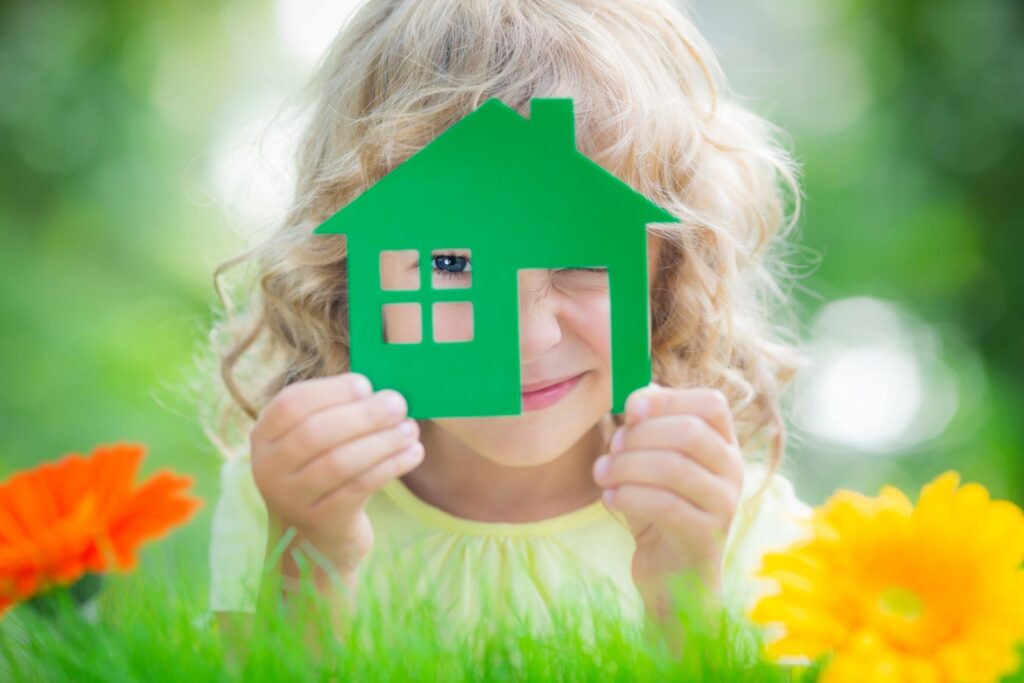 Une petite fille regarde au travers d'une silhouette de maison verte