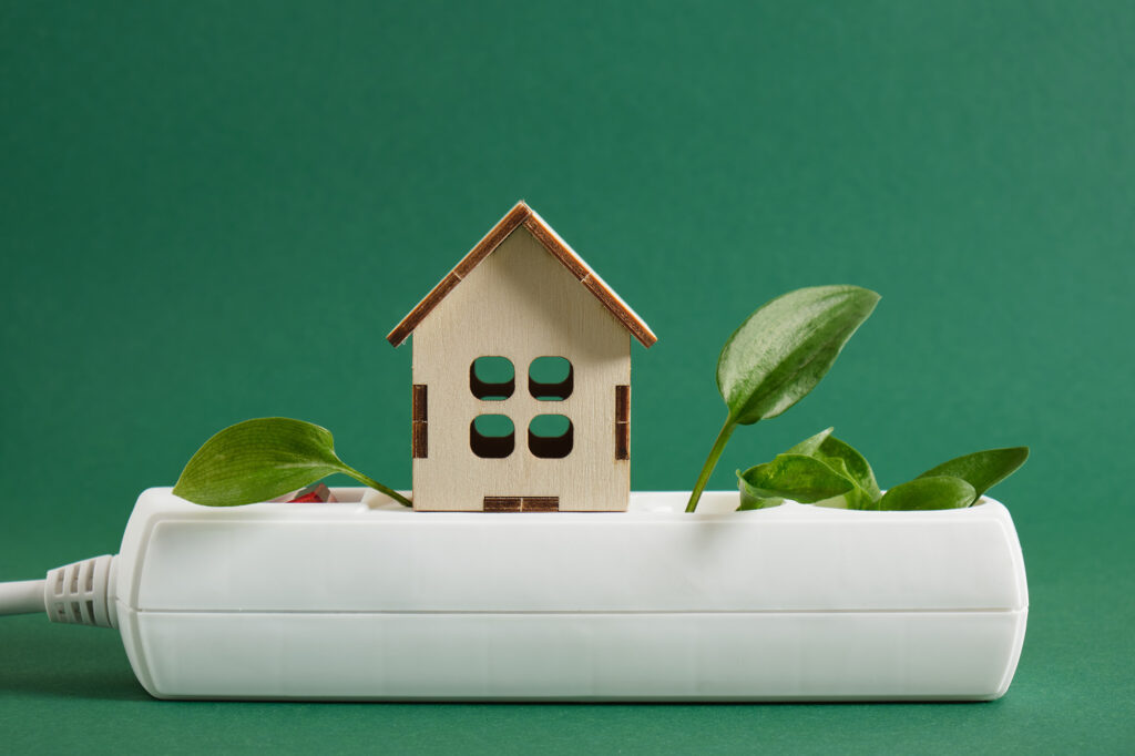 Maquette de maison basse consommation sur une prise électrique
